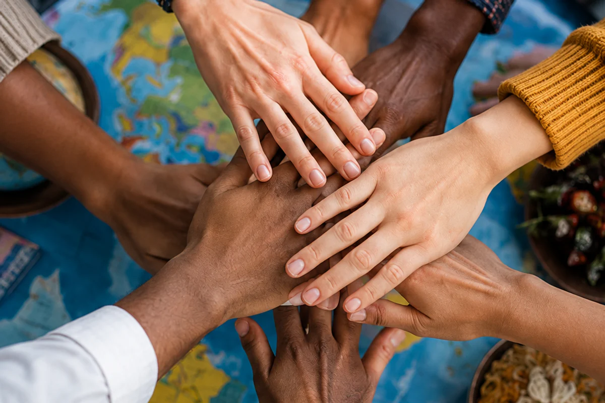 Mãos de pessoas de diferentes culturas reunidas sobre um mapa
